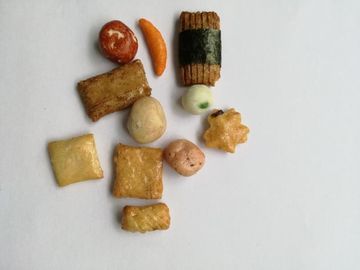 上塗を施してあるピーナツ グリーンピースが付いているシャキッとした焼かれた米のクラッカーの組合せ
